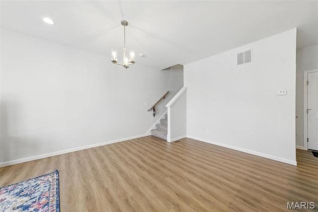 unfurnished living room featuring stairway, light wood-type flooring, a chandelier, baseboards, and recessed lighting