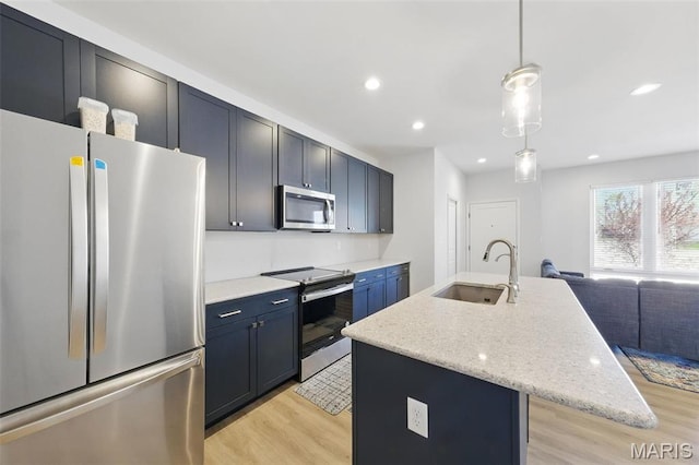 kitchen with appliances with stainless steel finishes, a sink, light wood-style flooring, a center island with sink, and recessed lighting