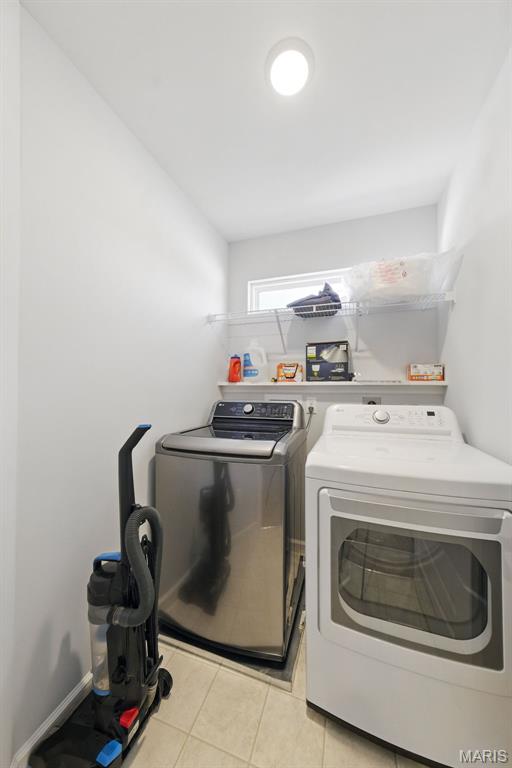 laundry area with washing machine and dryer and light tile patterned floors