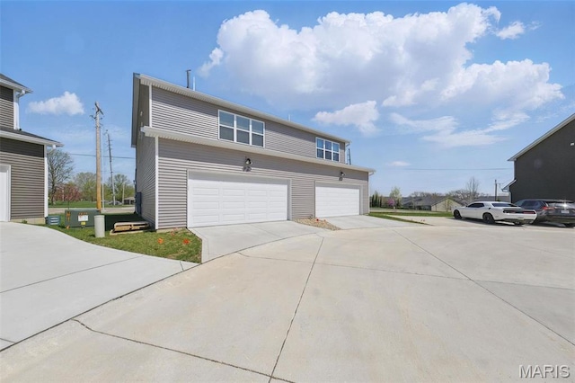 view of side of property with concrete driveway and an attached garage