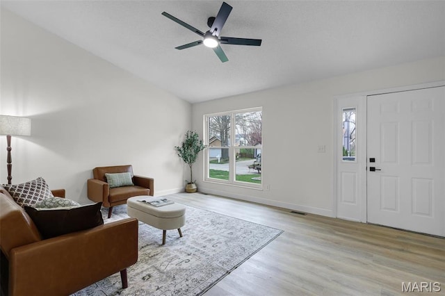 living room with vaulted ceiling, ceiling fan, wood finished floors, and baseboards