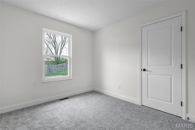 spare room with carpet flooring, a textured ceiling, and baseboards