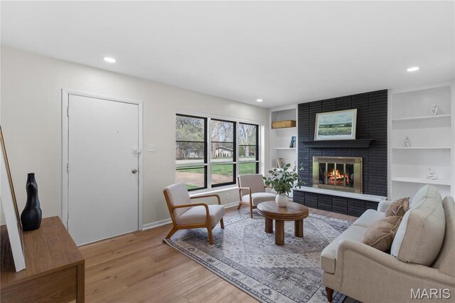 4410 Robbins Mill Rd, Florissant, MO 63034 - living area with light wood-style flooring, a fireplace, recessed lighting, baseboards, and built in shelves