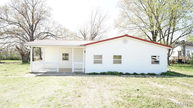 view of front of home with covered porch, a front lawn, and metal roof