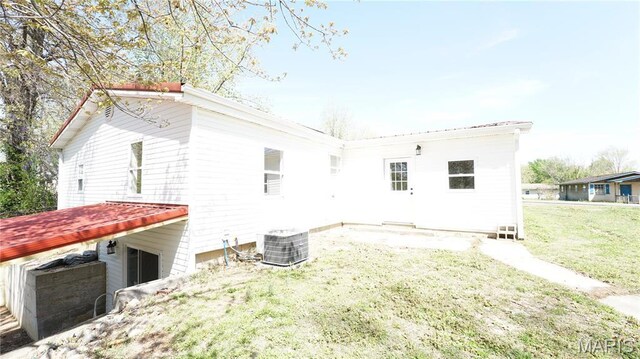 back of house with a lawn and central air condition unit