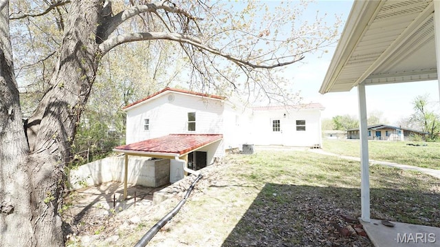 rear view of property with central air condition unit, a yard, and metal roof