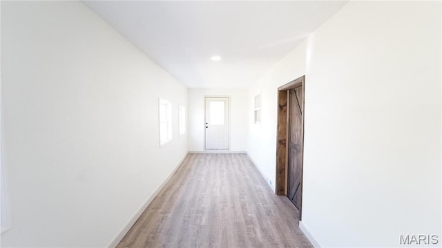 corridor featuring light wood-style flooring and baseboards