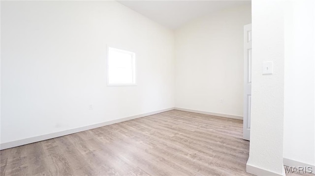 spare room with wood finished floors, lofted ceiling, and baseboards