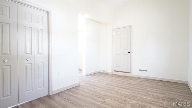 unfurnished bedroom with baseboards, wood finished floors, and a closet