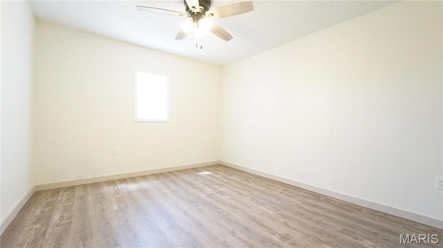 spare room featuring wood finished floors, a ceiling fan, and baseboards