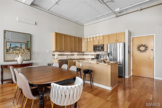 dining area featuring a high ceiling and light wood finished floors