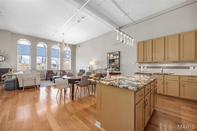 kitchen featuring a sink, light wood finished floors, rail lighting, and a high ceiling