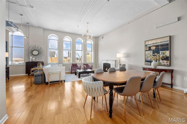 dining area with light wood finished floors, baseboards, a textured ceiling, and a chandelier