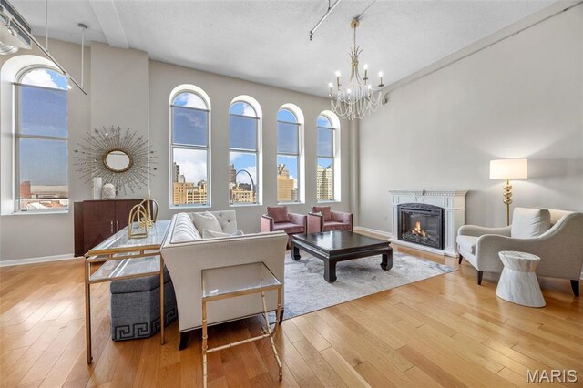 living area with hardwood / wood-style floors, a glass covered fireplace, a chandelier, and plenty of natural light