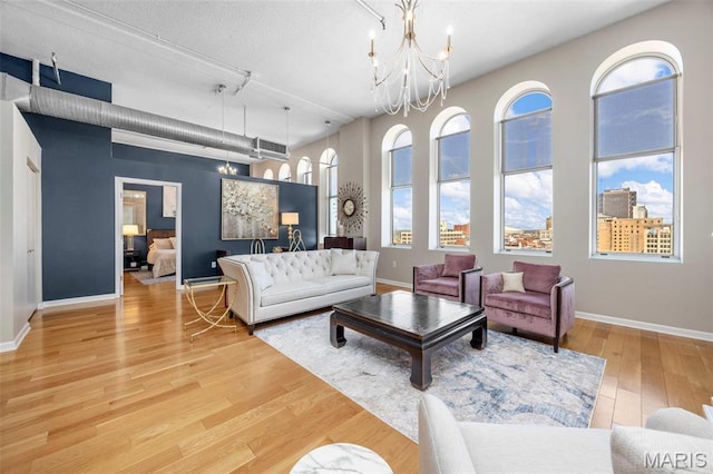 living area featuring a chandelier, wood finished floors, baseboards, and healthy amount of natural light