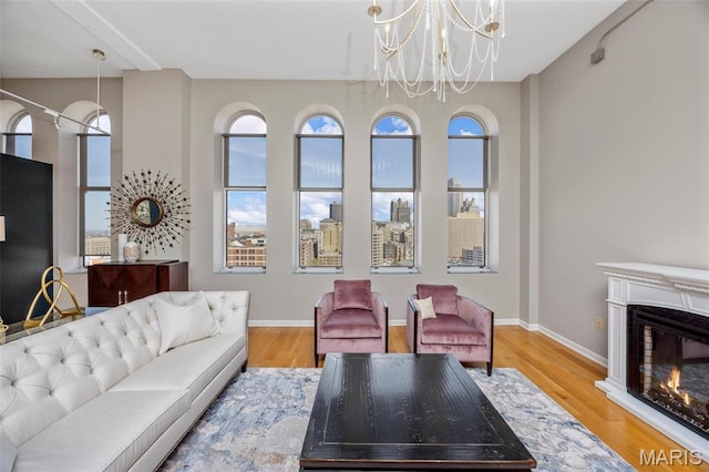 living area with wood finished floors, a chandelier, a glass covered fireplace, and baseboards