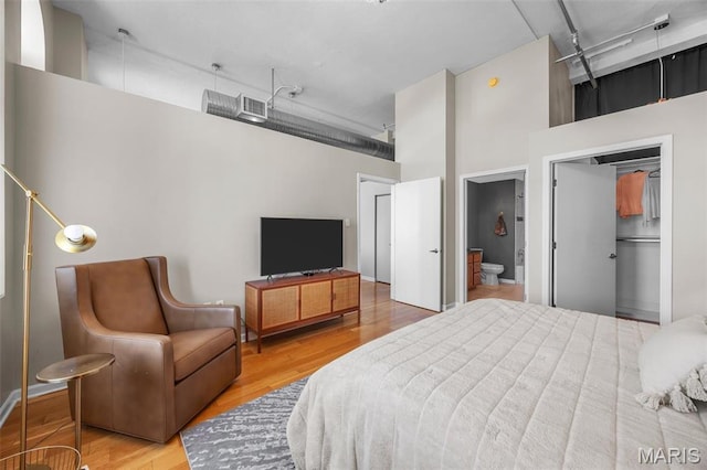 bedroom featuring a high ceiling, wood finished floors, and ensuite bathroom