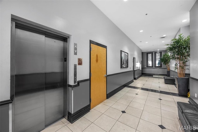 hallway featuring elevator, light tile patterned floors, inlaid floor details, and recessed lighting