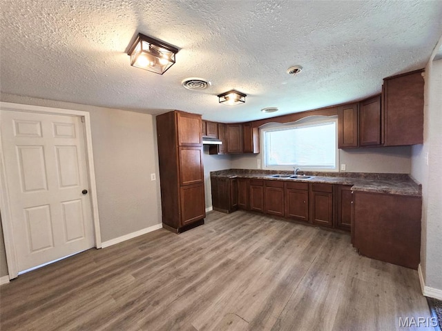 828 W Elk St, Dexter, MO 63841 - kitchen featuring a sink, dark countertops, light wood finished floors, baseboards, and a textured ceiling