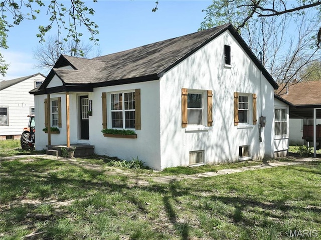 view of front of property with a shingled roof, a front yard, and stucco siding