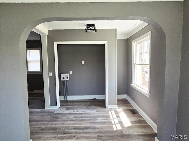 entrance foyer with arched walkways, wood finished floors, and baseboards