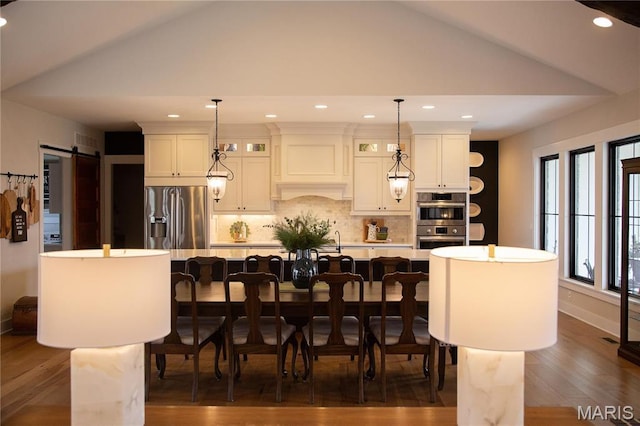 3 Inland Ct, Wright City, MO 63390 - kitchen with stainless steel appliances, lofted ceiling, a large island with sink, backsplash, and a breakfast bar area