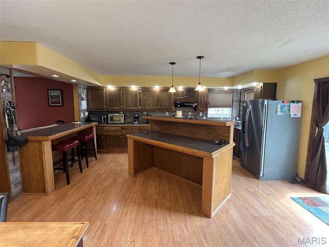 10303 Woodberry Rd, Potosi, MO 63664 - kitchen with stainless steel fridge with ice dispenser, a textured ceiling, light wood-style floors, a center island, and dark brown cabinets