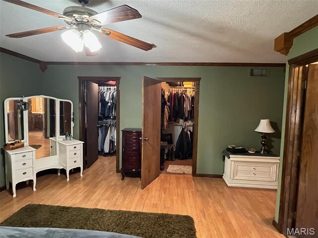 10303 Woodberry Rd, Potosi, MO 63664 - bedroom featuring crown molding, a walk in closet, light wood-style floors, a textured ceiling, and a ceiling fan