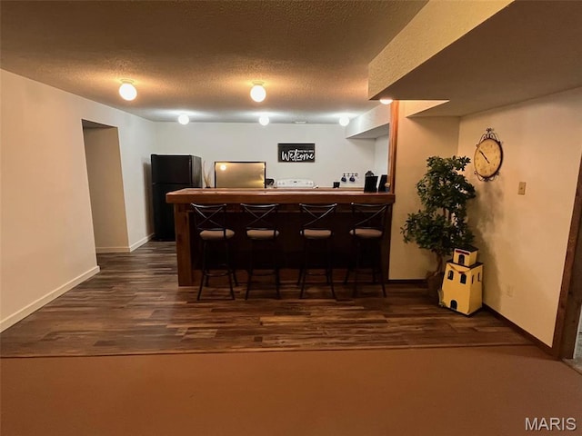 10303 Woodberry Rd, Potosi, MO 63664 - indoor dry bar featuring freestanding refrigerator, refrigerator, dark wood-type flooring, baseboards, and a textured ceiling