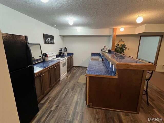 10303 Woodberry Rd, Potosi, MO 63664 - kitchen featuring electric stove, freestanding refrigerator, a kitchen bar, a sink, and dark wood-type flooring