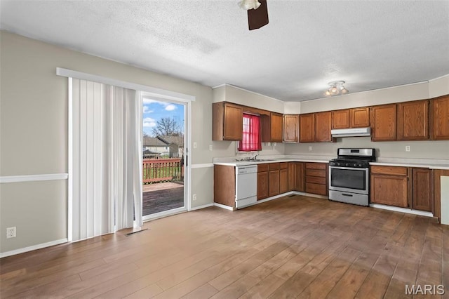 1112 N Illinois Ave, Litchfield, IL 62056 - kitchen with stainless steel range with gas stovetop, under cabinet range hood, white dishwasher, light countertops, and brown cabinets
