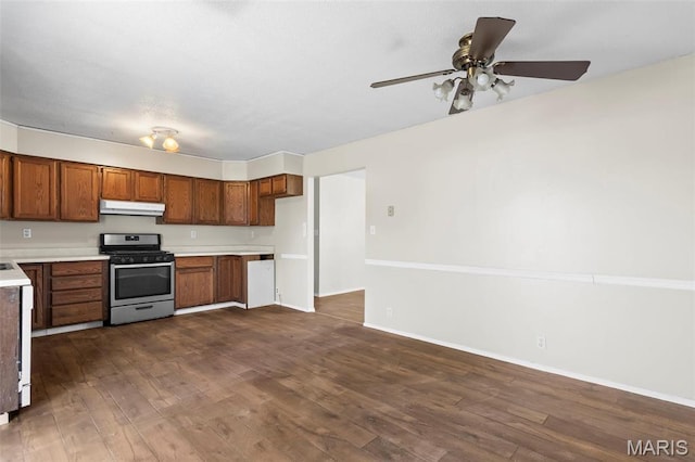 1112 N Illinois Ave, Litchfield, IL 62056 - kitchen with stainless steel range with gas cooktop, brown cabinets, under cabinet range hood, light countertops, and dark wood-type flooring