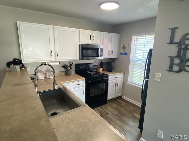 kitchen featuring stainless steel microwave, electric range, a sink, and white cabinetry