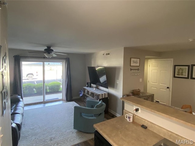living area featuring ceiling fan, dark wood finished floors, and baseboards