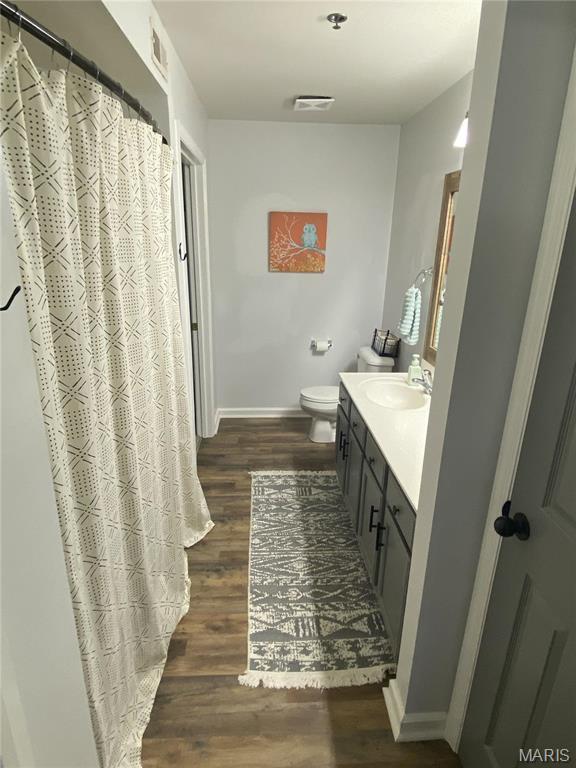 full bath with wood finished floors, vanity, baseboards, toilet, and a shower with curtain