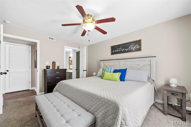 carpeted bedroom featuring baseboards, a ceiling fan, and ensuite bath