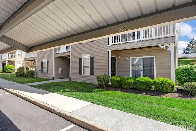 view of front of property featuring a balcony and a front yard