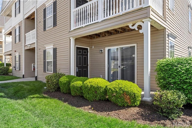property entrance with a balcony and a yard