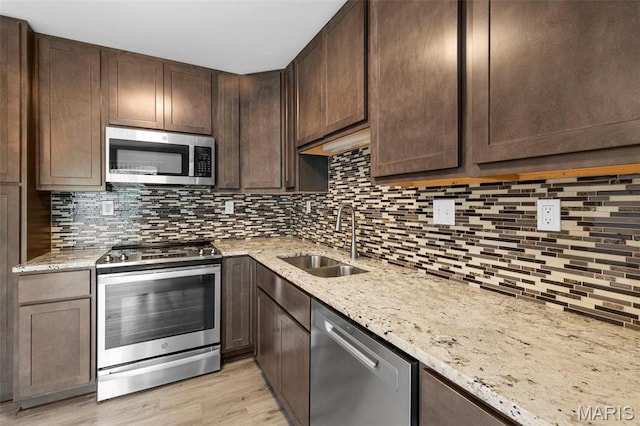 11148 Whispering Oaks Dr, Saint Louis, MO 63136 - kitchen featuring appliances with stainless steel finishes, a sink, dark brown cabinetry, and decorative backsplash