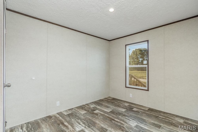 empty room featuring wood finished floors, a textured ceiling, and ornamental molding