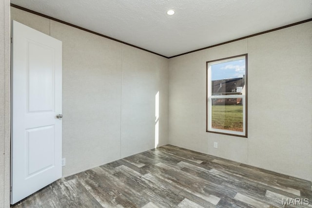 empty room with wood finished floors, ornamental molding, and a textured ceiling