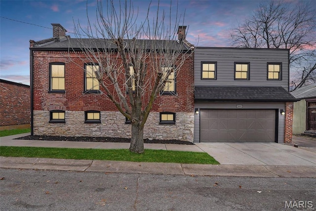 view of property featuring a chimney, a garage, concrete driveway, brick siding, and roof with shingles