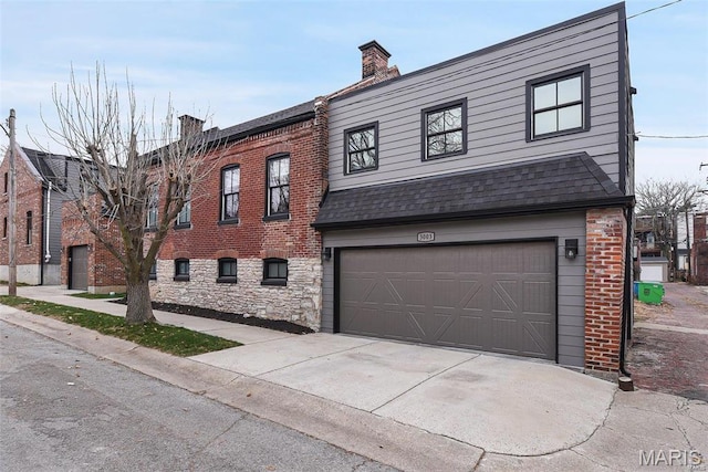 view of front of property featuring an attached garage, brick siding, a shingled roof, concrete driveway, and a chimney