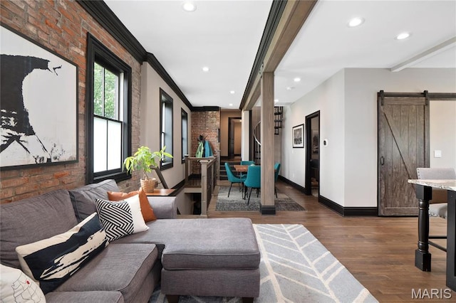 living area with a barn door, dark wood-style flooring, brick wall, recessed lighting, and baseboards