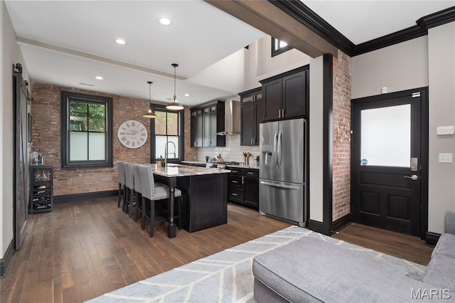 kitchen with stainless steel refrigerator with ice dispenser, a breakfast bar, baseboards, dark wood-type flooring, and brick wall