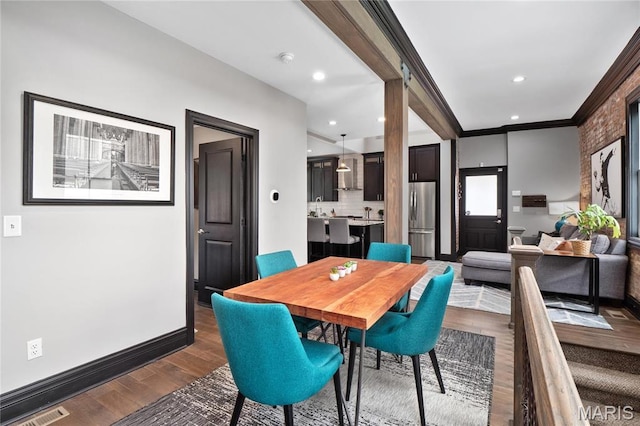 dining room featuring dark wood-type flooring, crown molding, baseboards, and recessed lighting