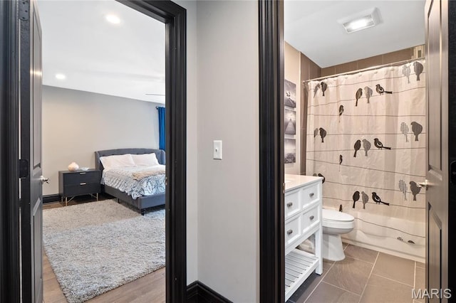 ensuite bathroom featuring toilet, curtained shower, and vanity