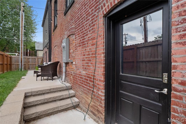 property entrance featuring brick siding and fence