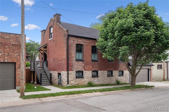 view of home's exterior featuring concrete driveway, a garage, brick siding, stairway, and a shingled roof