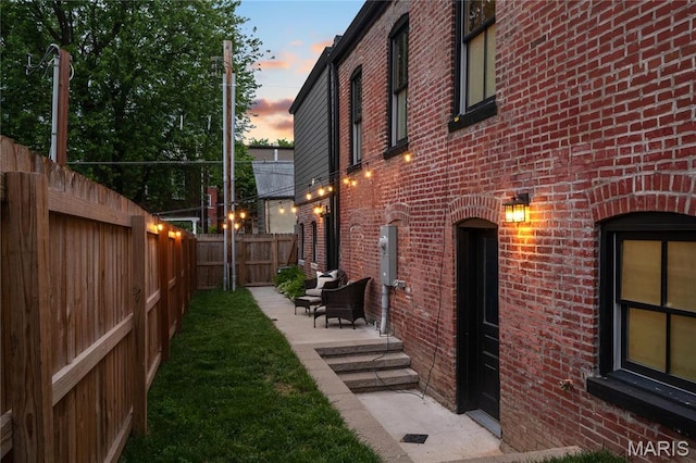 view of property exterior featuring brick siding, a fenced backyard, and a patio area